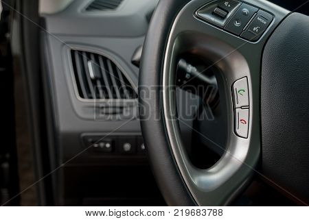 Car interior on the black leather of steering with hands free buttons green and red telephone symbol and mode of volumn modern car interior for safty driver.