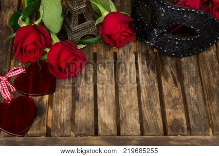 red fresh roses with masque and eiffel tower on wooden table, romantic date concept