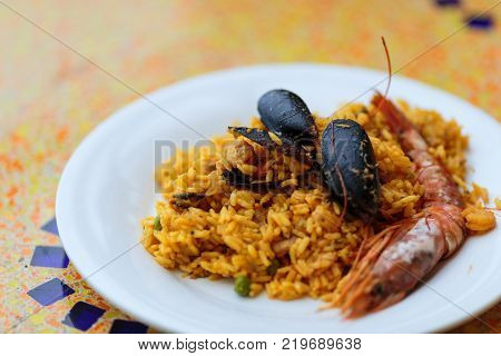 Royal Paella. Tasty Rice with king prawns, mussels and lemon on white plate