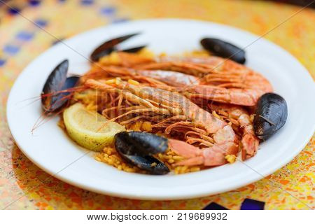 Royal Paella. Tasty Rice with king prawns, mussels and lemon on white plate
