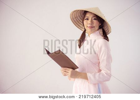 beautiful woman in pink dress and vietnam hat holding book