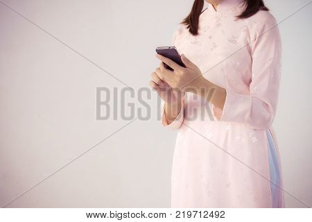 beautiful woman in pink dress and vietnam hat holding smartphone.