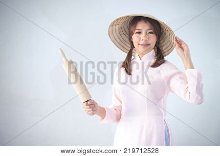 beautiful woman in pink dress and vietnam hat holding rolling pin.
