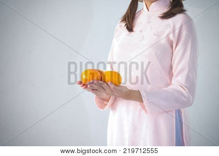 beautiful woman in pink dress and vietnam hat holding orange