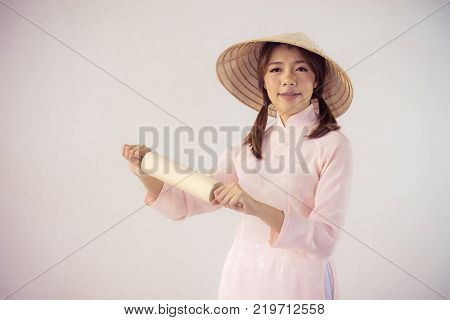 beautiful woman in pink dress and vietnam hat holding rolling pin.