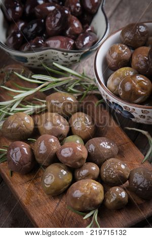 Cured, pickled or brined olive fruit on wooden table