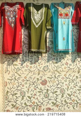 Colorful embroidered Indian women wear Chudidar kurtas hanging on the street shop. Indian textile and clothes.