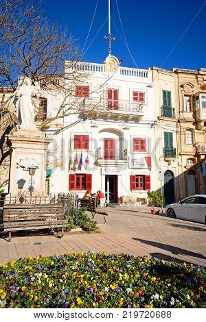 NAXXAR, MALTA - APRIL 2, 2017 - Statue of Madonna and child in the Pjazza Vittorja with the Red Cafe to the rear Naxxar Malta Europe, April 2, 2017.
