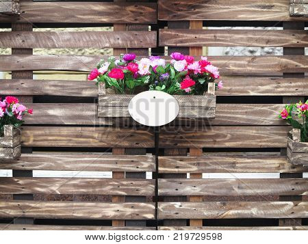 Old brown wooden fense with red flowers in boxes