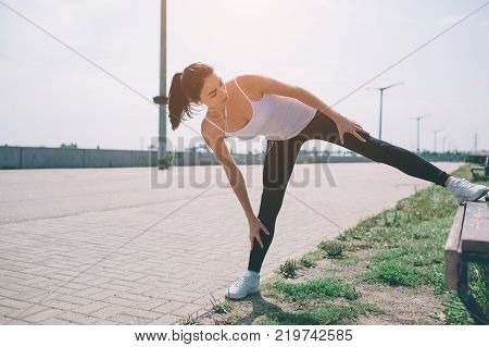 Young fitness woman runner stretching legs before run.