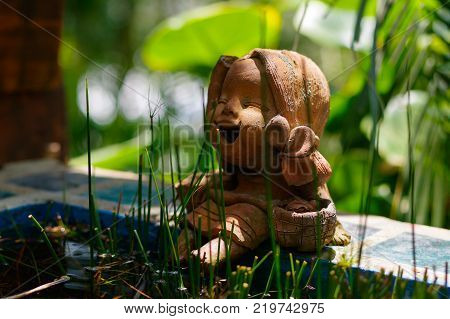 Little laughing buddha betwin grass in a garden