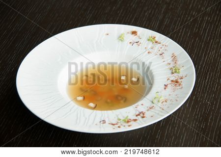 vegtable clear soup in a white bowl