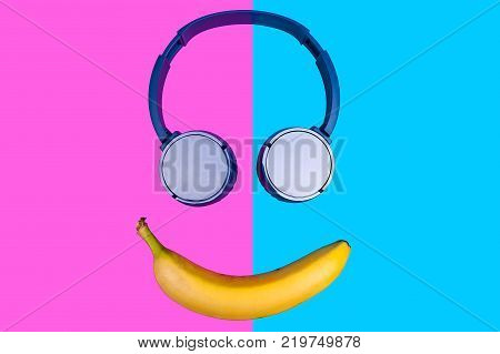 Pop art flat concept of banana and headphones on vivid colored background forming a smile face. Flat style and colors