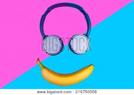 Pop art flat concept of banana and headphones on vivid colored background forming a smile face. Flat style and colors