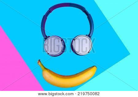 Pop art flat concept of banana and headphones on vivid colored background forming a smile face. Flat style and colors