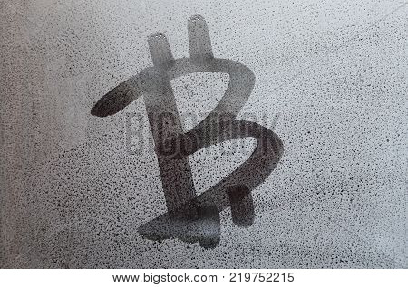 The bitcoin symbol on the misted sweaty glass. Abstract background image. Cryptocurrency concept