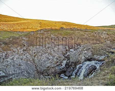 Waterfall From The Thawed Waters. Melting Snow In The Hilly Tundra. Waterfall