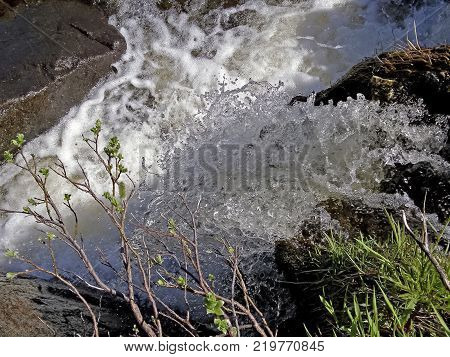 Waterfall from the thawed waters. Melting snow in the hilly tundra. Waterfall