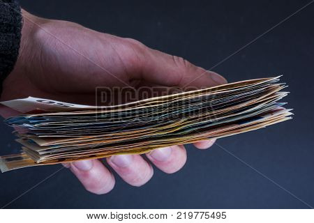 Human hand holding money - fifty-twenty-ten euro banknotes isolated on a dark gray background