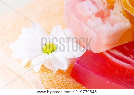 Facecare and bodycare concept. A close up of a fresh cut white flower, colorful fruit soap bars on a terry towel. Space for a text or product display.