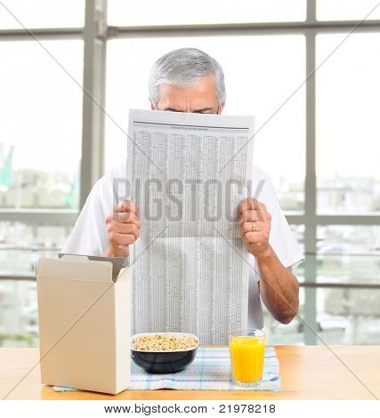 Casually dressed uomo di mezza età leggendo il giornale del mattino davanti alla grande finestra con Ferrara