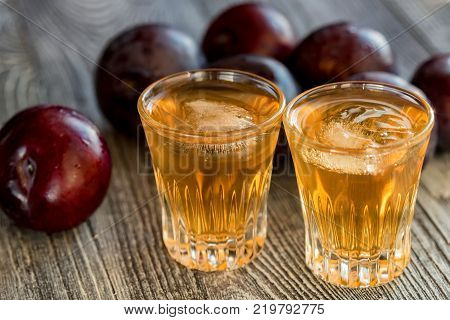 Plum liqueur or slivovitz, plum rakia with fresh and tasty plum on rustic wooden background
