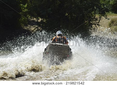 The man on the ATV crosses a stream. Tourist walks on a cross-country terrain.
