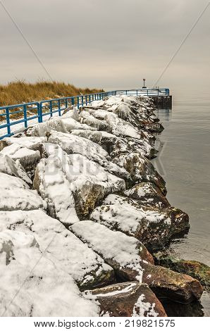 Ice covered rocks along the White River. The pierhead light sits at the edge of Lake Michigan.