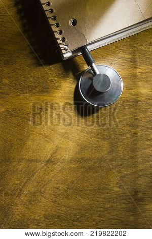 Stethoscope of a doctor in a notebook on a wooden table