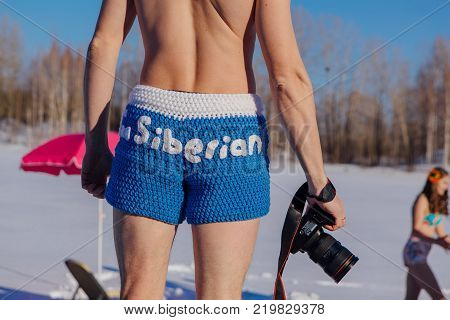 Novokuznetsk, Kemerovo region, Russia - 23 Feb, 2017 : White beaches of Siberia is an enterteiment activity where people playing beach games dressed in bikini in winter. Man in blue shorts with camera