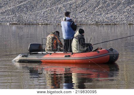 boy fishing . an old man sitting in a boat with a fishing rod. view from the back. floats
