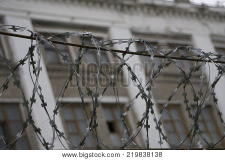 wire barrier with beautiful sky clouds and brick building behind the scene.