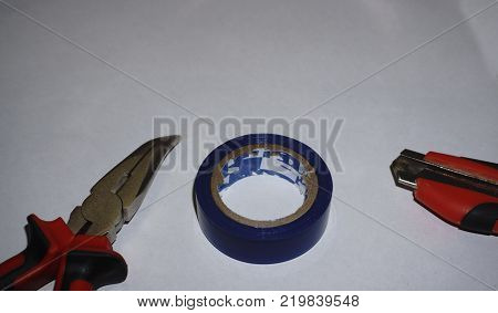 Top view shot of utility knife spatula notebook and pliers on graph paper