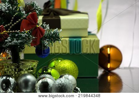 Cute green gift with red christmas balls on green abstract light background