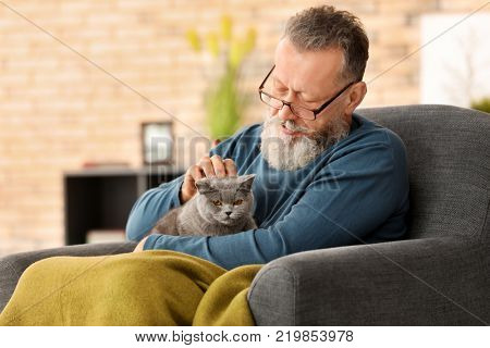 Senior man holding cute cat at home