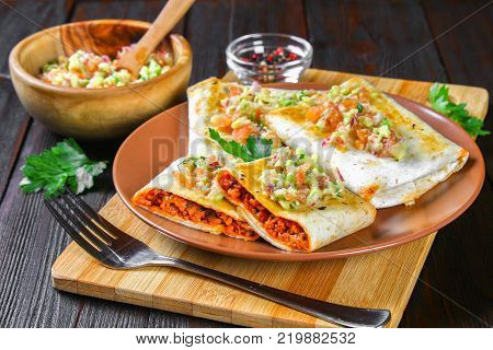 Traditional Mexican dish - chimichanga. Corn cake with minced meat, pepper, onion, garlic, oregano, zira and guacomole sauce from avocado