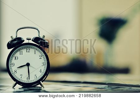 Retro vintage style classic white alarm clock on vintage bedroom background for daylight saving or time concept.