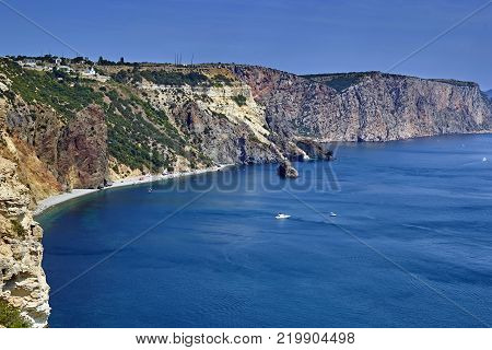 Sea bay with cliffs in the background of mountains and blue sky. Bay with clean water in a sunny summer day.