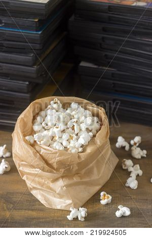 Pop corn and laser discs on a wooden surface. Rustic style, selective focus.