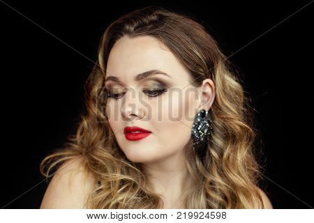 Portrait of a young beautiful woman with red lipstick on a black background. Makeup. Holidays.