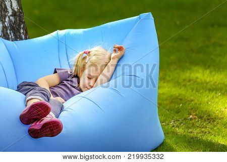 Young cute blond girl sleeping on an inflatable bed outdoors.