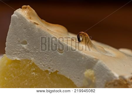 Lemon meringue pie on cutting board on brown wooden background