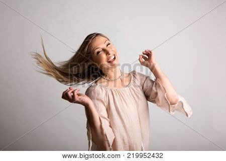 Smiling vivacious carefree woman flicking long blonde hair