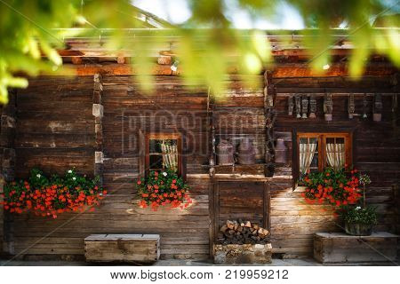 Wooden house with red flowers and cowbells.