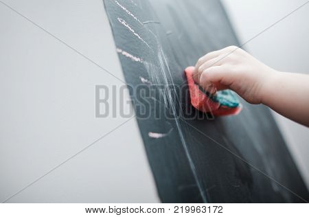 Cute little girl drawing on blackboard. Toddler girl having fun outdoors, holding chalk and drawing.