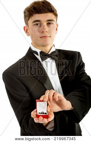 18 year old wearing a tuxedo smiling oepning a ring box isolated on a white background