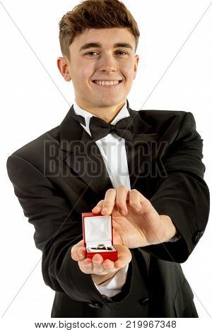 18 year old wearing a tuxedo smiling oepning a ring box isolated on a white background
