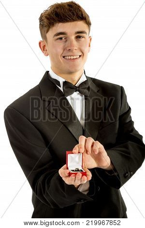 18 year old wearing a tuxedo smiling oepning a ring box isolated on a white background