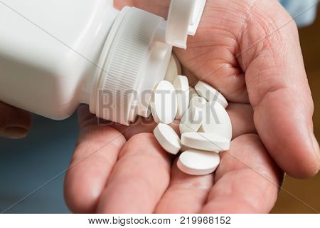 White medication pills, calcium dietary supplement in the woman palm hand.