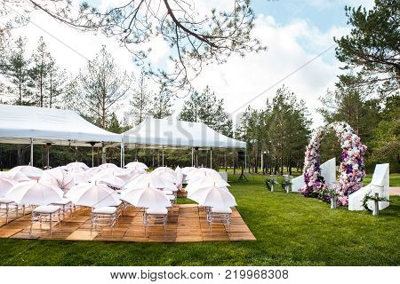 Outdoor wedding ceremony with umbrellas in the forest.